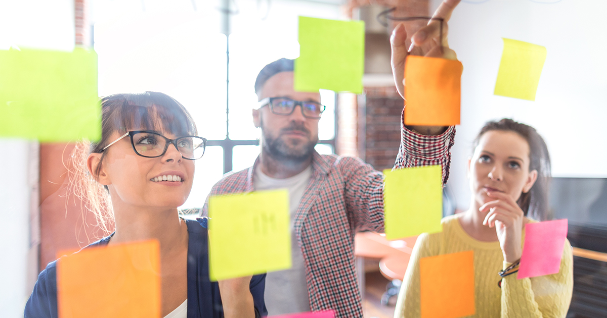 People looking at sticky notes on a wall