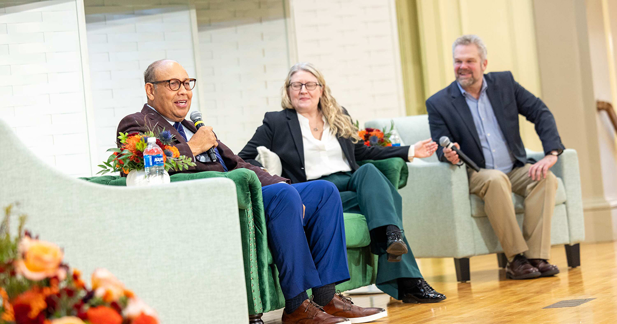 Speakers sit on a stage for a panel