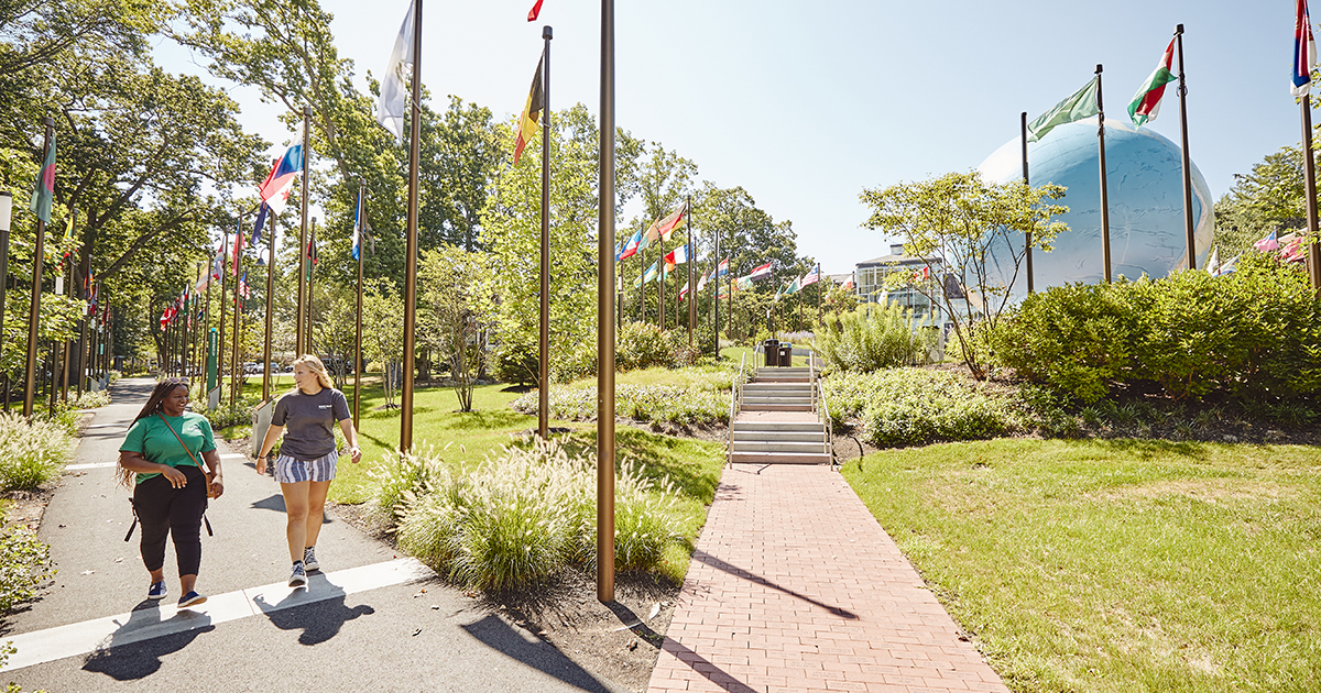 Students walking by the globe on a sunny summer day