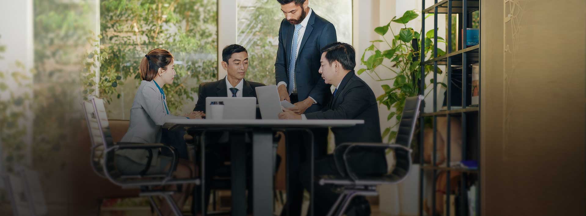 Businessmen talking and looking at laptops